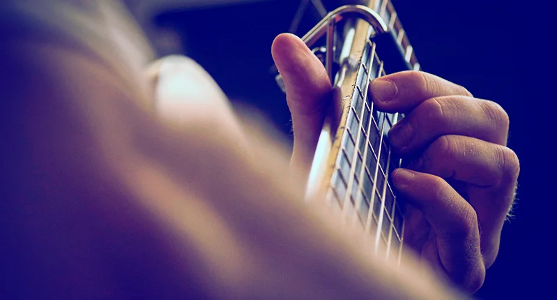 Una mano suona la chitarra durante la preghiera